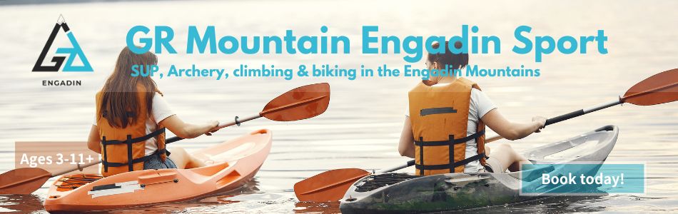 Two children kayaking on a calm alpine lake, with the GR Mountain Engadin Sport camp banner promoting SUP, archery, climbing and biking for ages 3 to 11 plus