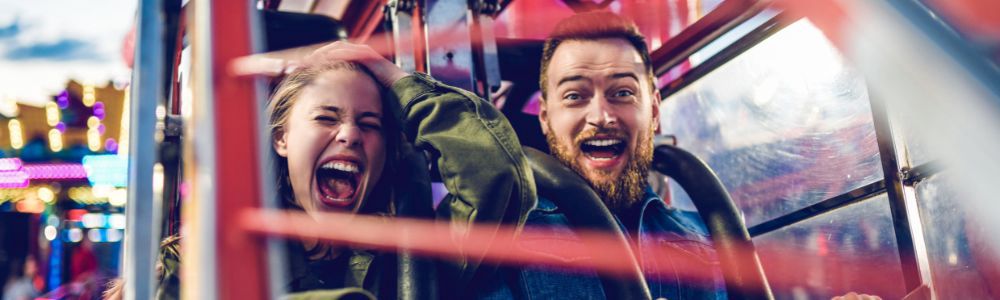 A young dad and his teenage daughter in a rollercoaster in Connyland, Switzerland are having a thrilling time, as the teenage girl is screaming and covering her eyes.  
