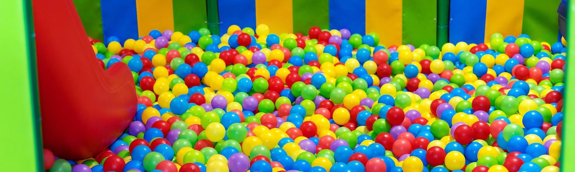 Colorful outdoor playground named 'Karamel Playground' featuring whimsical equipment resembling caramel shapes and sweets, set in a sunny, child-friendly park with trees and grassy areas.