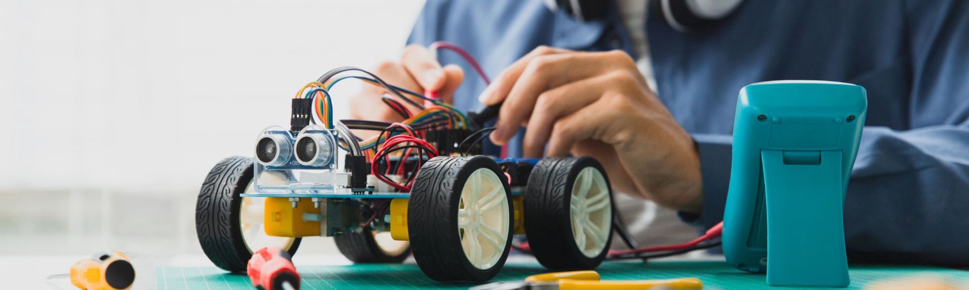 Children building and programming Lego robots at a TechKids workshop, using laptops and colorful Lego kits on tables.