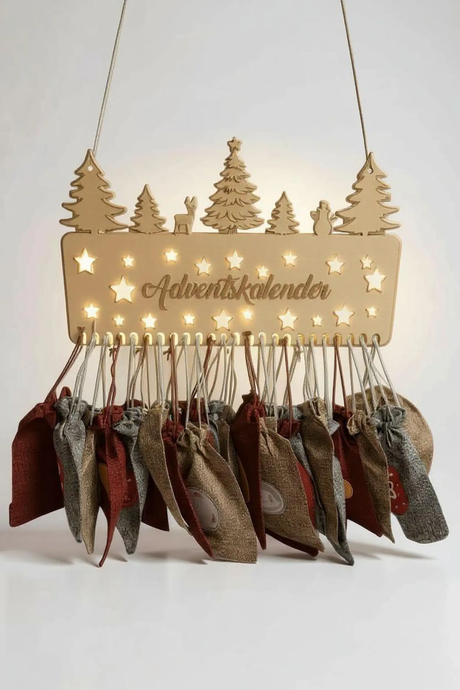 Beleuchteter Holz-Adventskalender mit 24 Säckli über dem Cheminée; zwei Kinder geniessen die Adventsstimmung am Feuer.