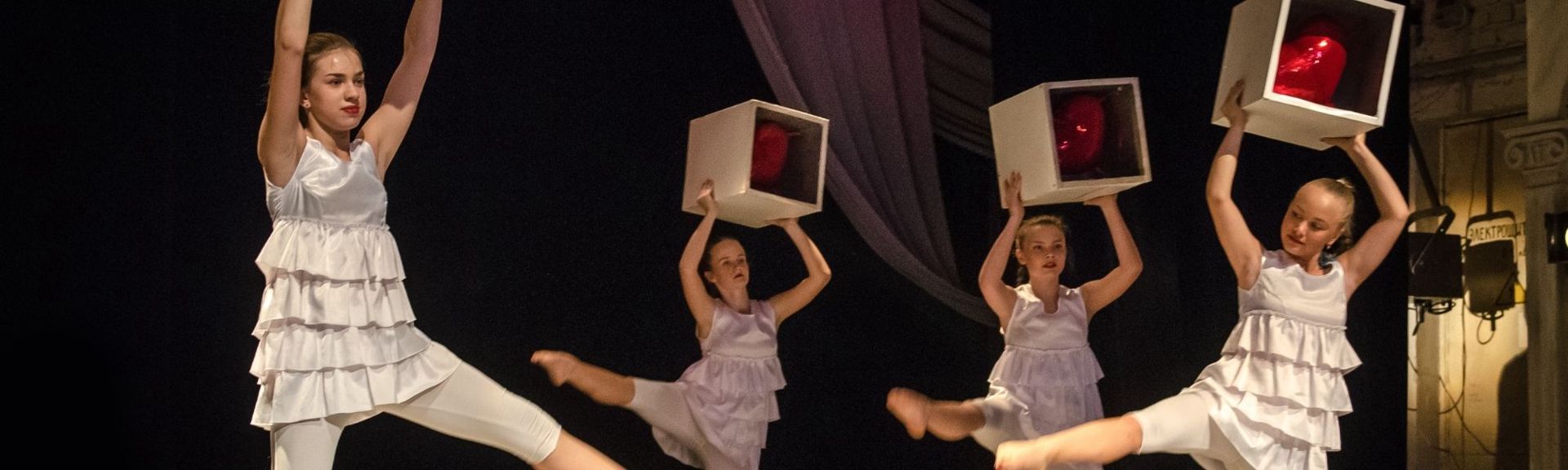 Children performing on stage at Simply Theatre Zug, dressed in costumes with theatrical lighting, as an audience watches in a cozy theatre setting.