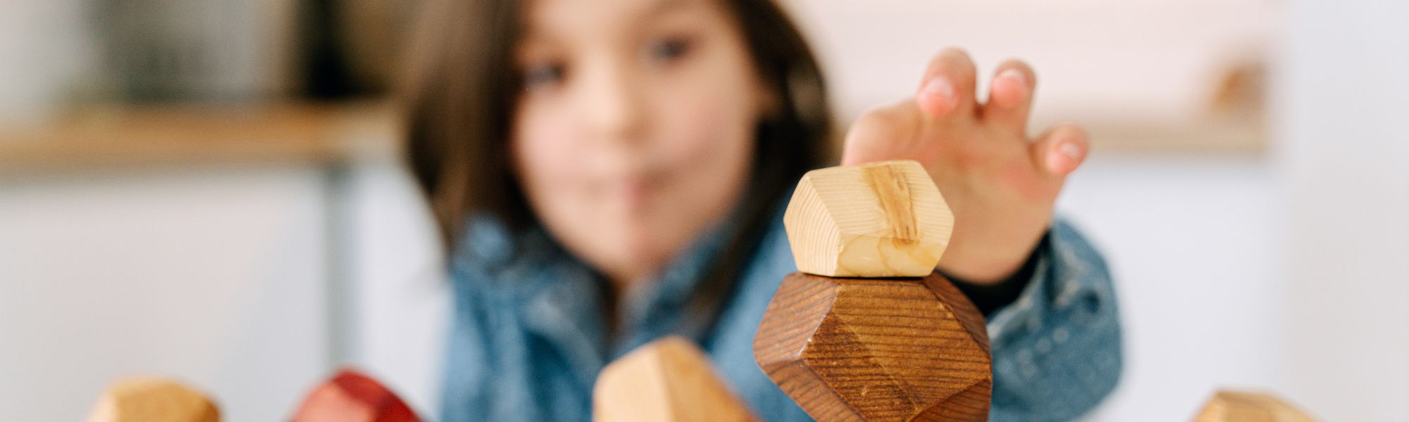 Young child playing with wooden geometric stacking blocks, a popular unisex gift idea for kids.