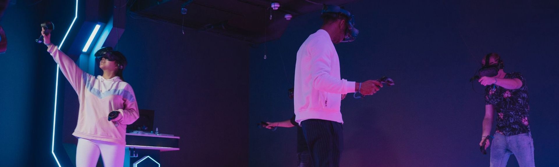 Young person wearing a VR headset and holding controllers at VR City, fully immersed in a virtual reality gaming experience inside a modern, neon-lit arena.
