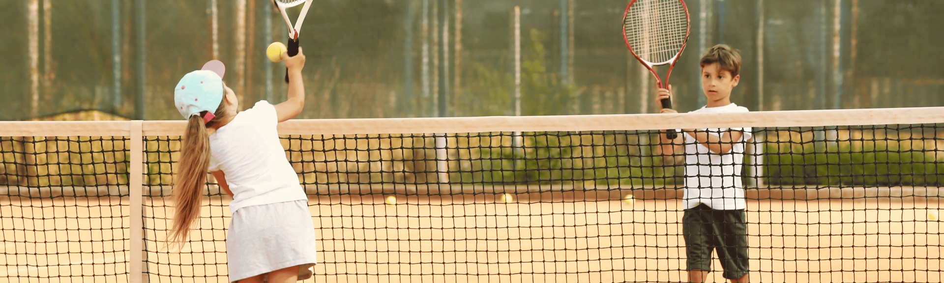 A tennis match between two teen kids, a girl and a boy in Baar, under the supervision of tennis coach Evan Bolofis in Baar, Switzerland