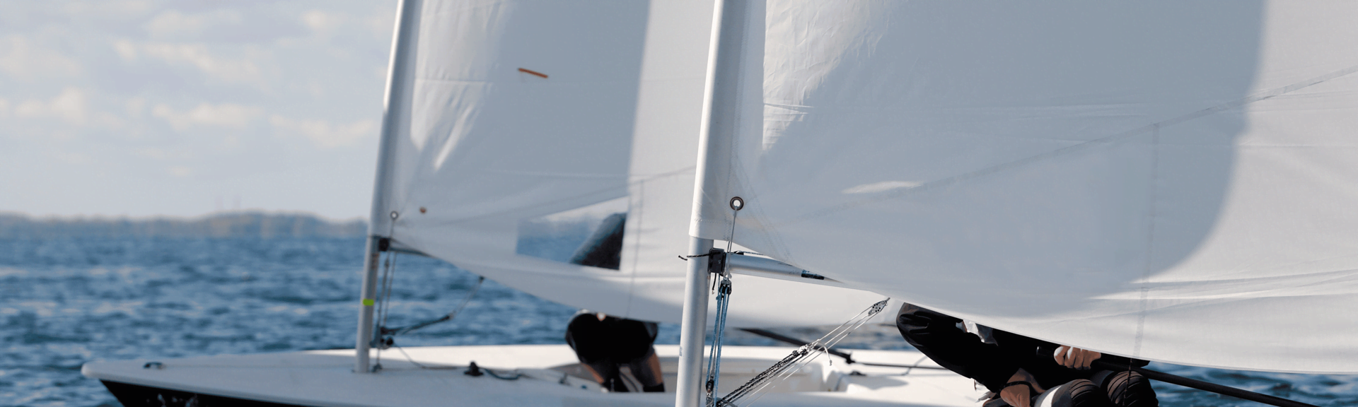 Two laser sail boats photographed sailing next to each other in a close-up to the mast at the sailing club in Voula, Athens, Greece.