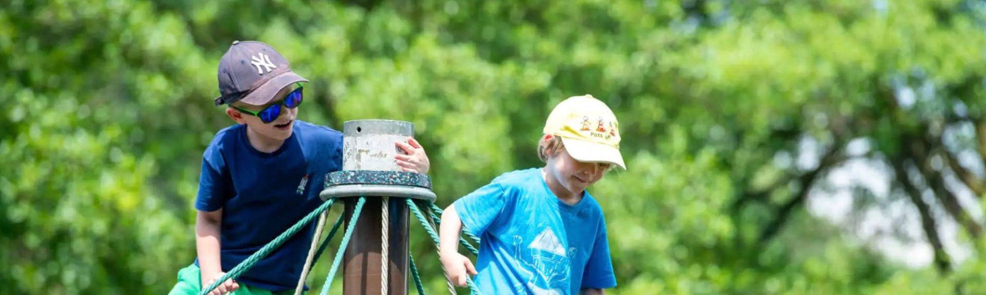 Two boys play on an outdoor climbing structure at FOUR Forest Zug, part of the school's bilingual forest school programme.