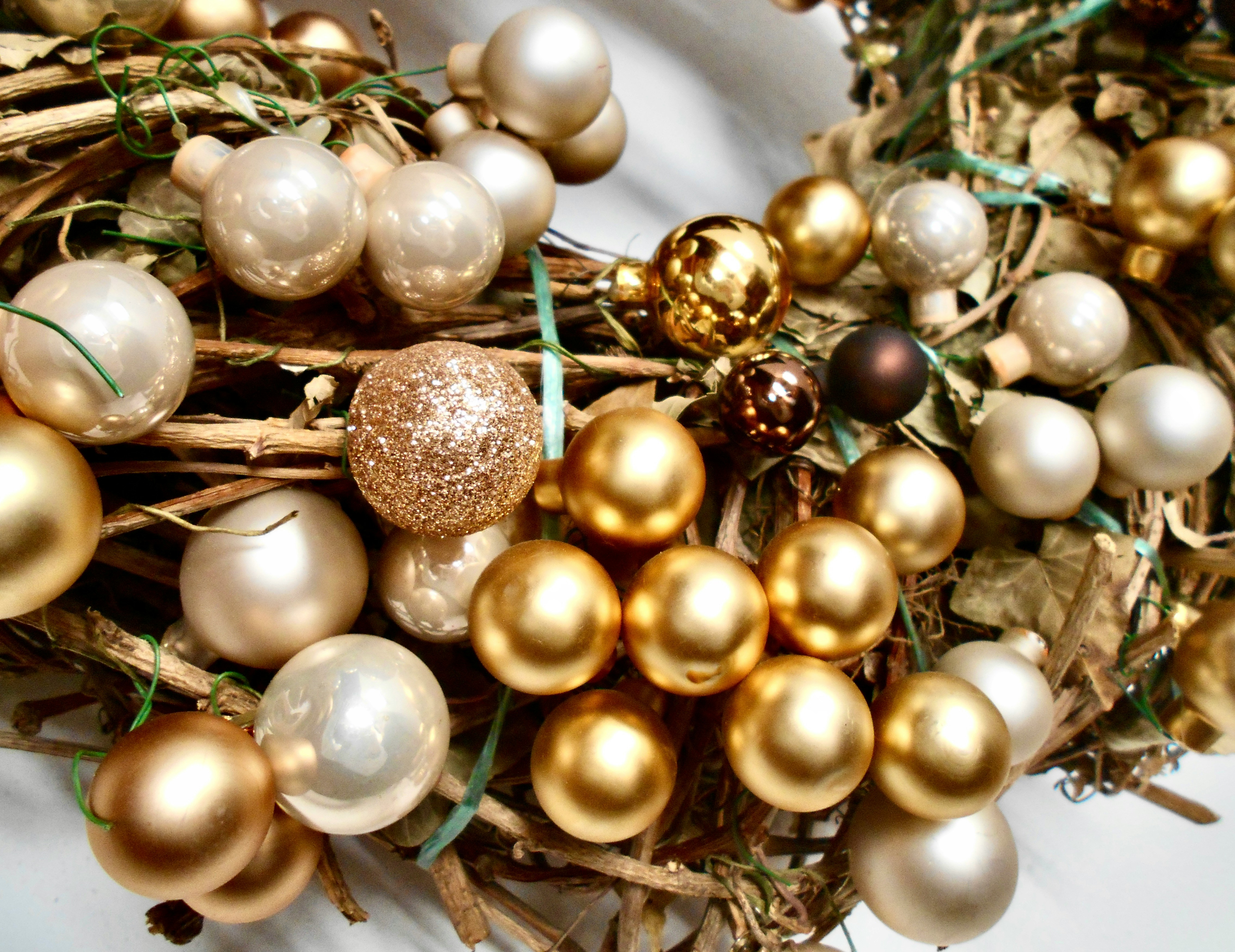 Festive holiday wreath adorned with gold and white Christmas ornaments, featuring glittery and shiny baubles, perfect for seasonal decoration. Photo by <a href="https://unsplash.com/@heyitspixi?utm_content=creditCopyText&utm_medium=referral&utm_source=unsplash">Anastasia Pixner</a> on <a href="https://unsplash.com/photos/a-bunch-of-gold-and-white-ornaments-sitting-on-top-of-a-table-rcLYUKjT_Wk?utm_content=creditCopyText&utm_medium=referral&utm_source=unsplash">Unsplash</a>