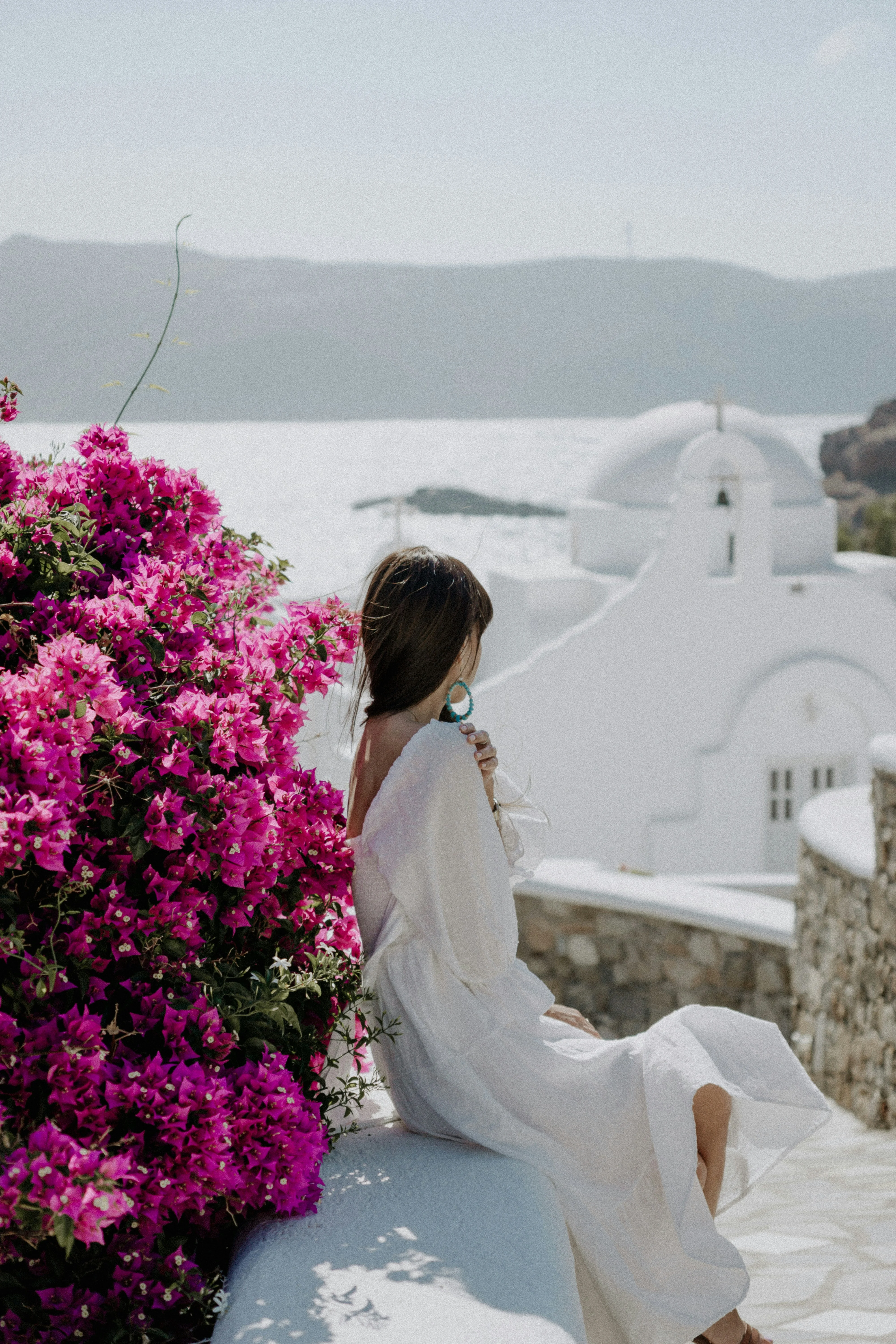 Κοπέλα κάθεται σε ένα κυκλαδίτικο πρεβάζι.