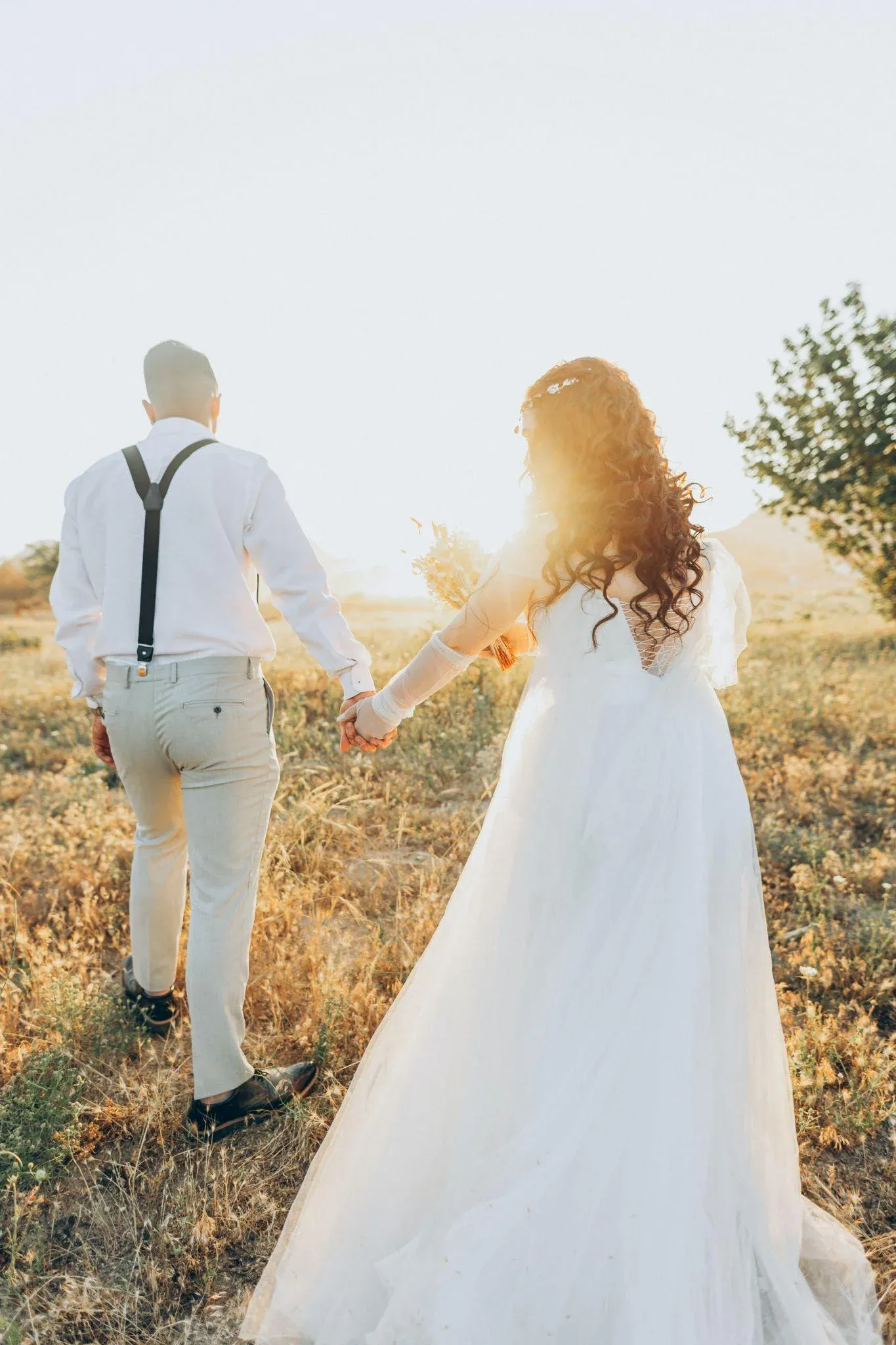 Wedding photographer capturing a couple during an outdoor photo session, with the bride and groom posing closely together.