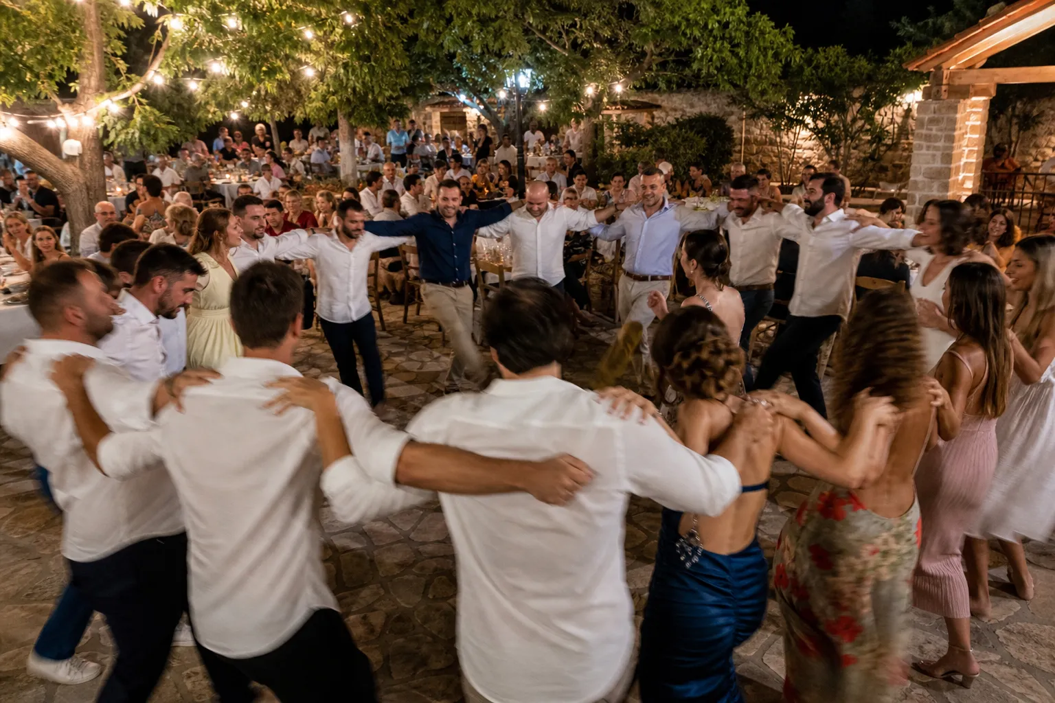 Καλεσμένοι μοιράζονται στιγμές σε δείπνο στην ελληνική ταράτσα με ηλιοβασίλεμα