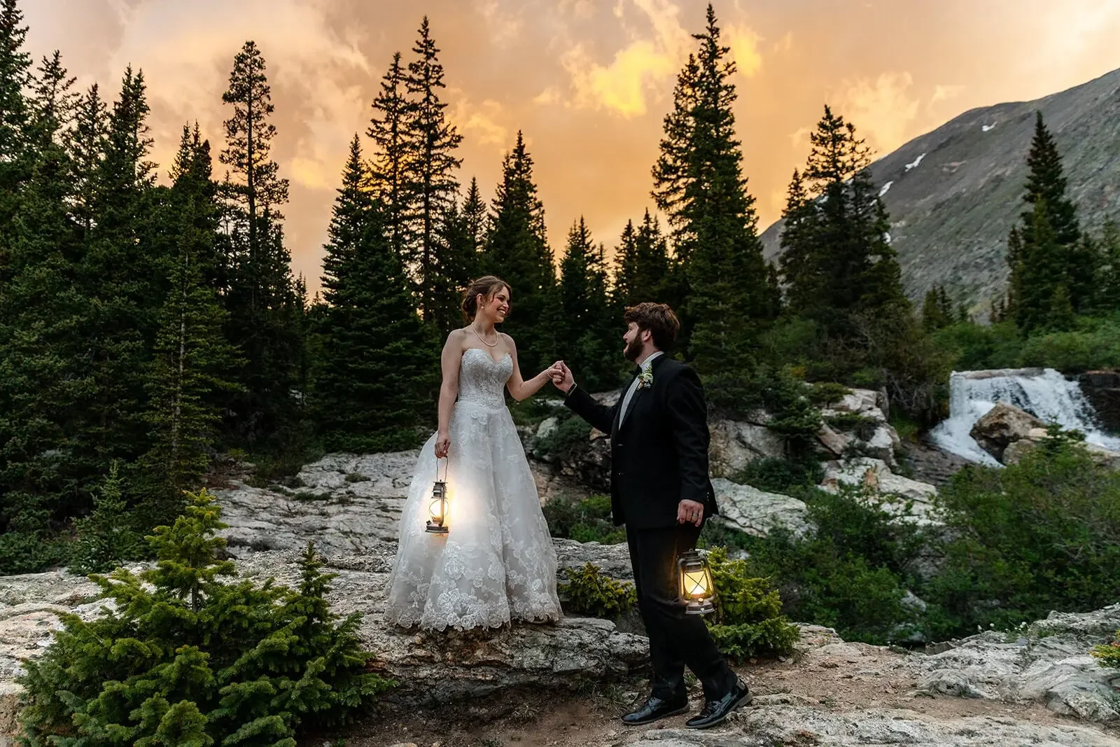 Colorado Outdoor Weddings ζευγάρι με φαναράκια στο ηλιοβασίλεμα δίπλα σε καταρράκτη