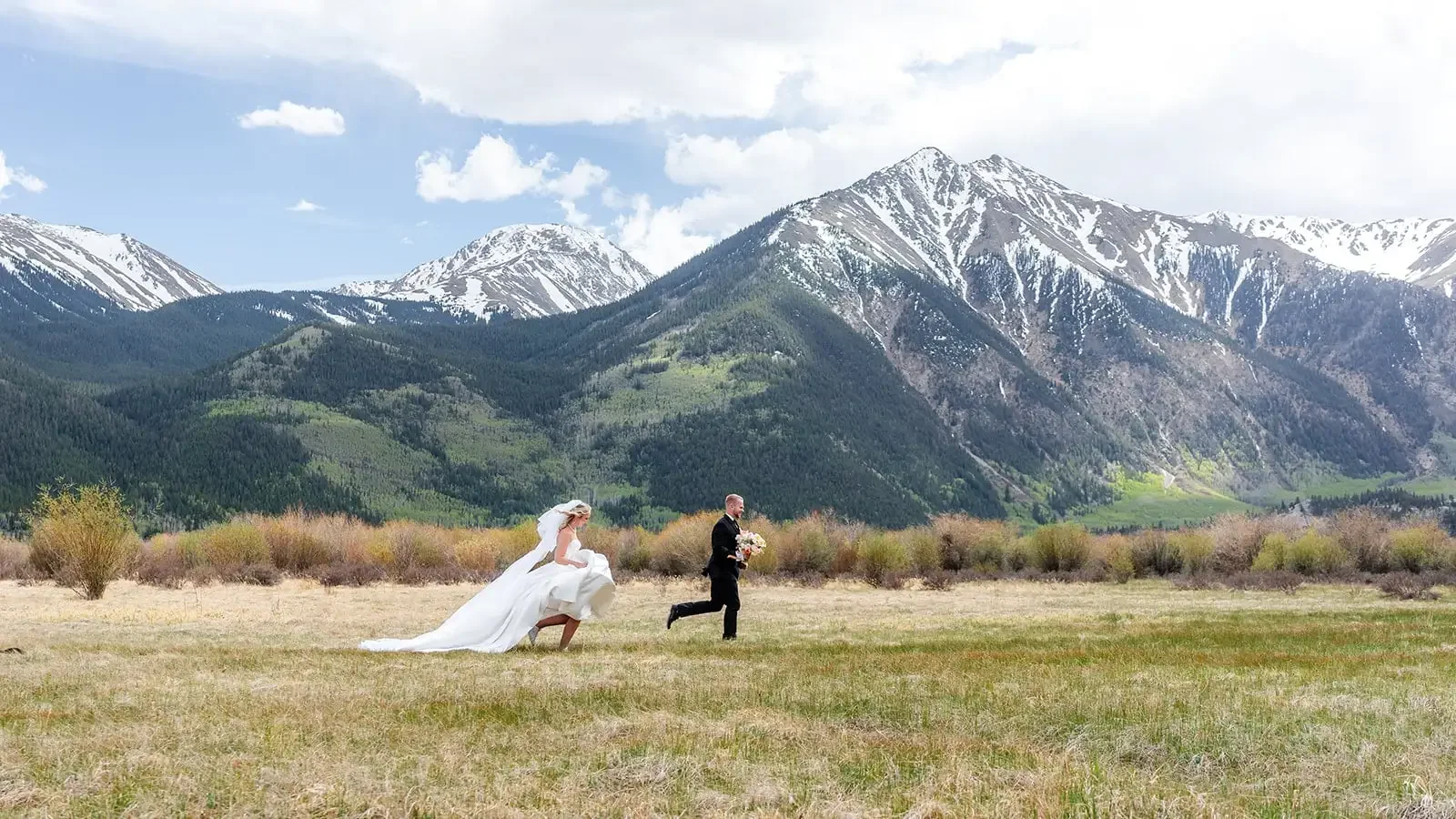 Colorado Outdoor Weddings ζευγάρι σε ορεινό λιβάδι κάτω από χιονισμένες κορυφές στο Κολοράντο