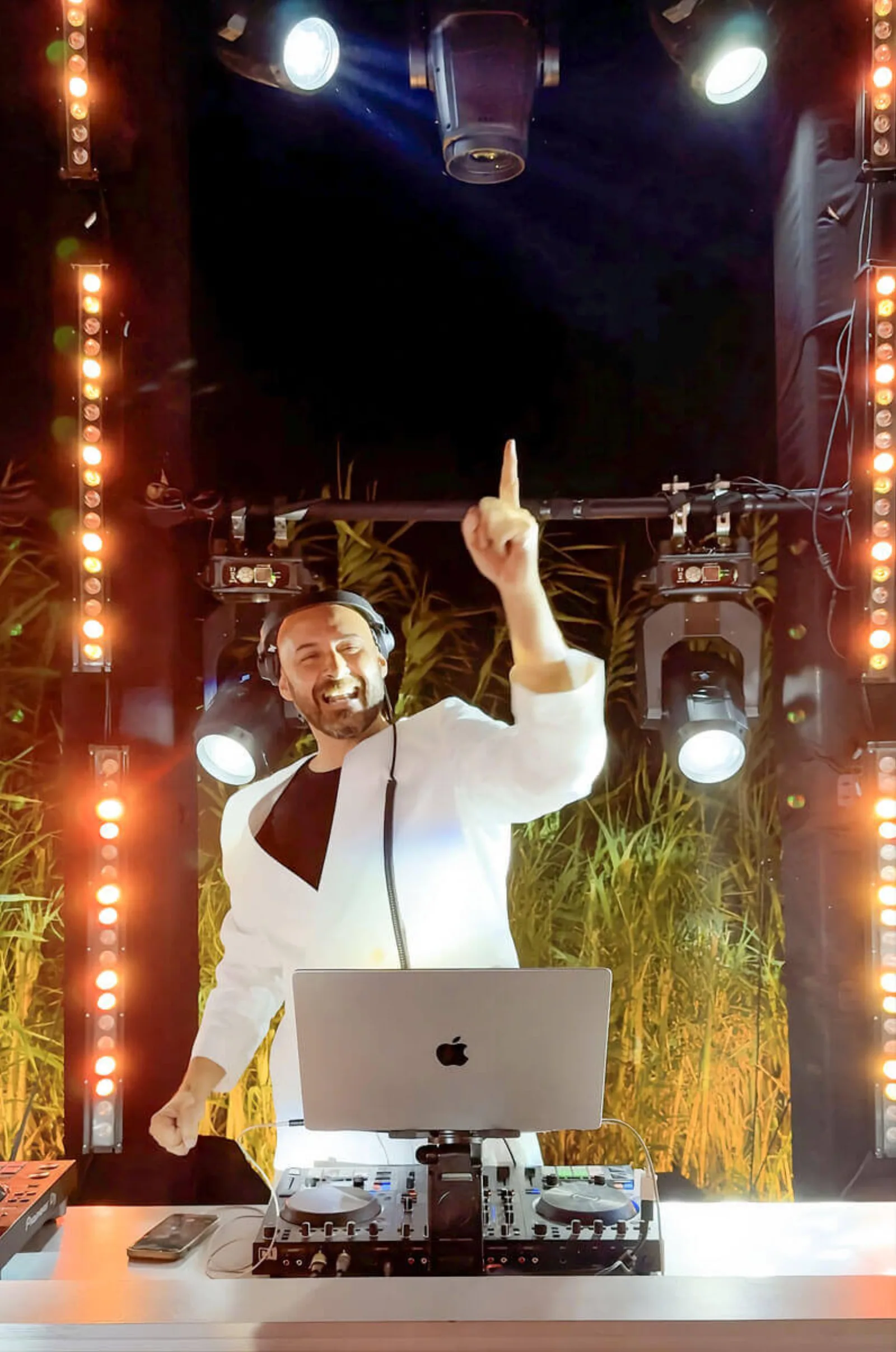 High-energy DJ γάμου με λευκό κοστούμι κάτω από party lights