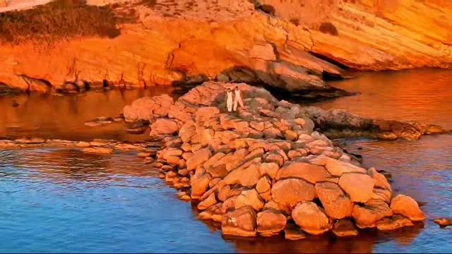 Drone view of red rocks and turquoise sea at sunset, Koufonisia
