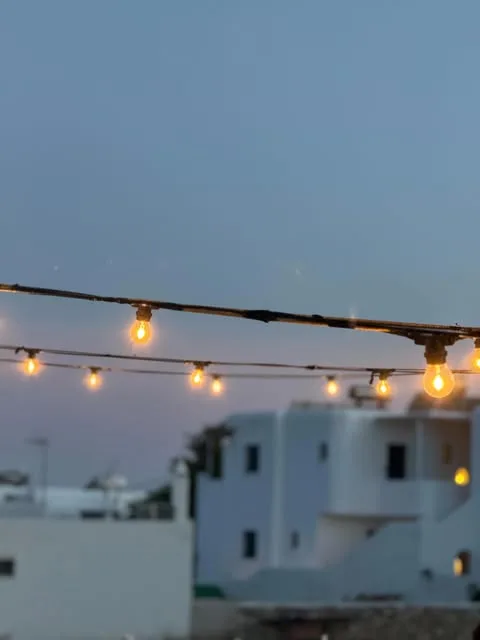 String lights over the whitewashed Chora at dusk, Stou Lolou