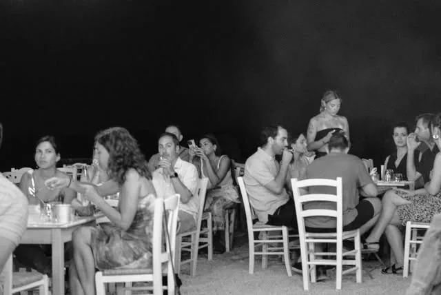 Guests dining at outdoor tables at night, Stou Lolou