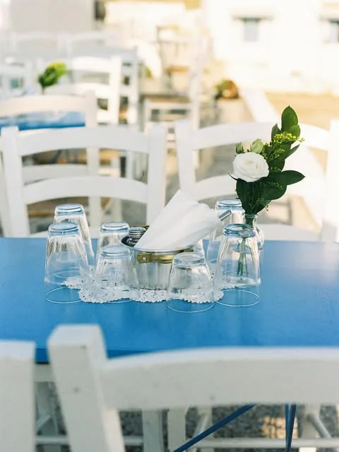 Blue table set with wine glasses and a white rose at Stou Lolou