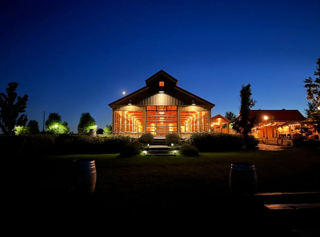 Το Barrel Barn του Trezzi Farm φωτισμένο τη νύχτα κάτω από σκούρο μπλε ουρανό