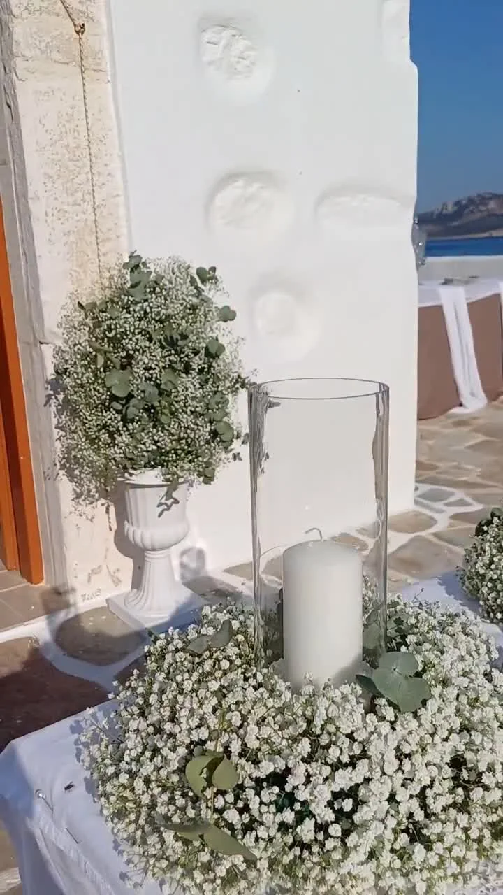 Xylobati sta Koufonisia ceremony table with gypsophila and candle on whitewashed Cycladic wall Koufonisia